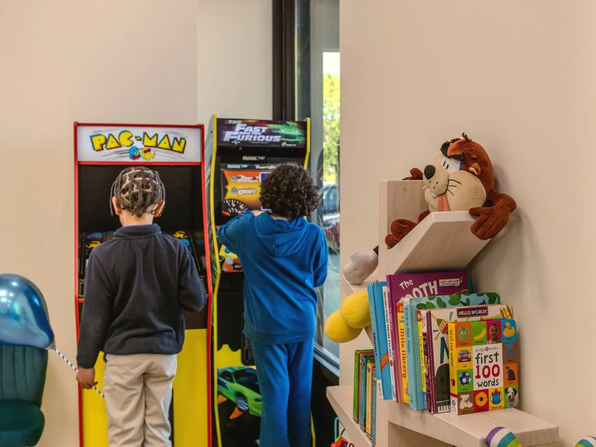 The Arcade — kids playing the arcade machines, seen from behind